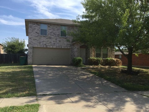 a white brick house with a driveway and a tree